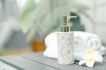 Cropped shot of Spa accessories with white towel, plumeria rubra flowers with bottles of creams, lotions, copy space on wood table