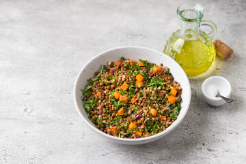 Buckwheat with vegetables and kale on a gray textured background, top view. Delicious healthy vegan food