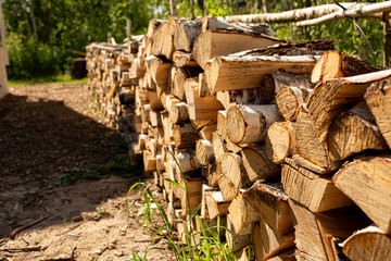 A woodpile with a billet and stacks of firewood from chopped wood for the furnace and heating of the house. Birch wood.