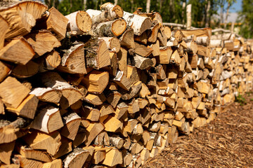 A woodpile with a billet and stacks of firewood from chopped wood for the furnace and heating of the house. Birch wood.