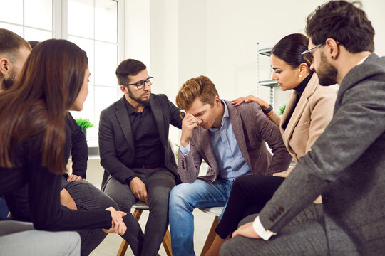 Everything will be fine. View of the group of young businessmen comforting their frustrated colleague. Teammates calms down upset male colleague. Dismissal, problems in the office.