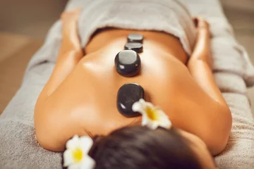Fotobehang Massagesalon Unrecognizable young man lying on a spa bed, relaxing, getting beauty treatments, and enjoying an exotic back massage with hot stones. Spa treatment, body relaxation, skin care concept