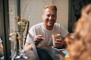 Happy man having conversation with faceless woman in cafe