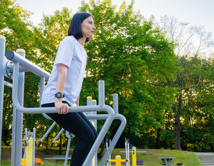 Woman doing triceps dip on parallel bars outdoors.push ups on parallel bars outdoors. Fitness and...