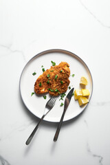 Baked Chicken Schnitzel on white plate with lemon. Rack or grid with baked schnitzel in breadcrumbs...