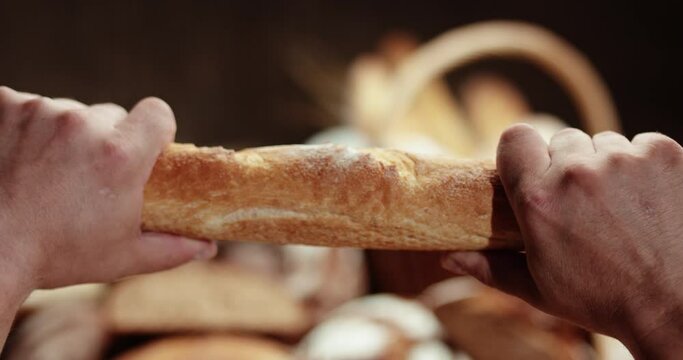The baker breaks a crispy baguette.