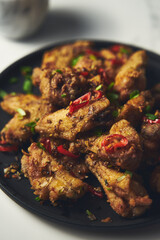 Chinese Salt and Pepper chicken wings. Crispy battered Deep fried chicken wings with vegetables seasoned with salt and pepper and then quickly sauteed with onions, garlic and chilies.