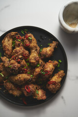 Chinese Salt and Pepper chicken wings. Crispy battered Deep fried chicken wings with vegetables seasoned with salt and pepper and then quickly sauteed with onions, garlic and chilies.