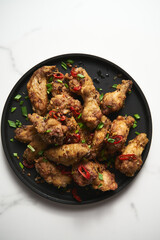 Chinese Salt and Pepper chicken wings. Crispy battered Deep fried chicken wings with vegetables seasoned with salt and pepper and then quickly sauteed with onions, garlic and chilies.
