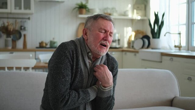 Pain on heart, heart attack. Unhappy middle aged senior man suffering from chest pain heart attack problems with health at home. Mature old senior grandfather touching chest experiencing infarction