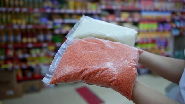 a woman in a supermarket chooses red lentils and rice