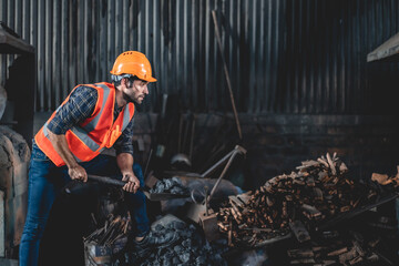 Obraz premium Mine worker man dressed in work overalls and a hard hat, Work in a coal mine, Plant worker throws coal into open-hearth melting furnace, working in coal mine factory and warehouse using spade to move