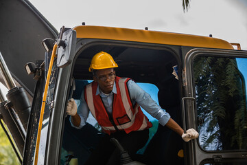 Naklejka premium Black people worker in helmet on site construction, Excavator bulldozer male worker, Construction driver with excavator on the background, Construction worker with tractor at ground building site