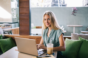 Portrait of skilled female blogger with digital netbook technology looking at camera during time...