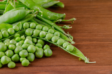 Green pea and pea pods. Pea on wooden table. Closeup of fresh pea. Pea pod with beans.