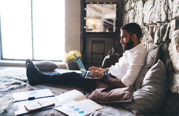 Focused ethnic man working on laptop