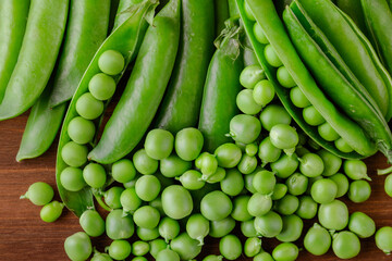 Green pea and pea pods. Pea on wooden table. Closeup of fresh pea. Pea pod with beans.