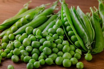 Green pea and pea pods. Pea on wooden table. Closeup of fresh pea. Pea pod with beans.