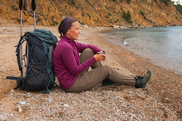 Hiking tourism adventure. Backpacker woman resting after hiking looking at beautiful view. Hiker girl lady tourist with backpack sitting near lake. Hiker woman enjoy hike tourism active vacation