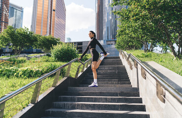 Female athlete stretching leg on stairs