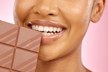 Woman, mouth and chocolate in studio closeup with smile, eating and skin glow for beauty by pink...