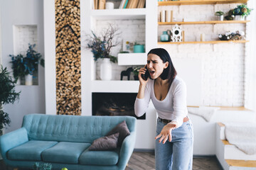 Fototapeta premium Angry woman talking on smartphone at home