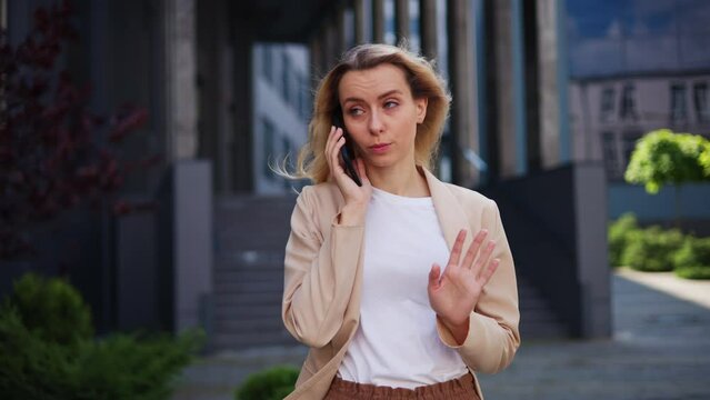 Angry assertive young businesswoman engaged in a passionate conversation on mobile phone outdoors. Unsatisfied female customer passionately expressing dissatisfaction and frustration subordinate.