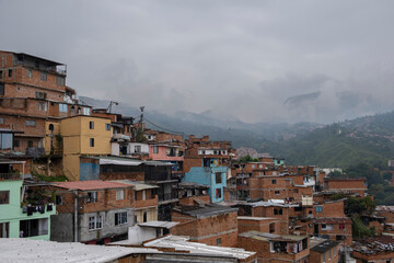 Aerial panoramic view of poor neighborhoods and favelas built of red brick in city's outskirt. Comuna 13, Medellin, Colombia. - obrazy, fototapety, plakaty