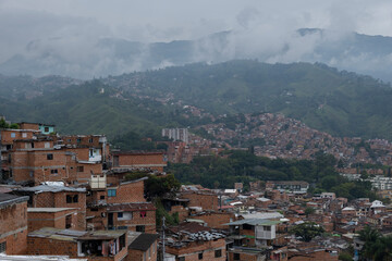 Aerial panoramic view of poor neighborhoods and favelas built of red brick in city's outskirt. Comuna 13, Medellin, Colombia.