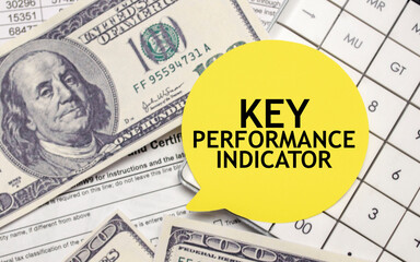 KEY PERFORMANCE INDICATOR words on yellow sticker with dollars and charts