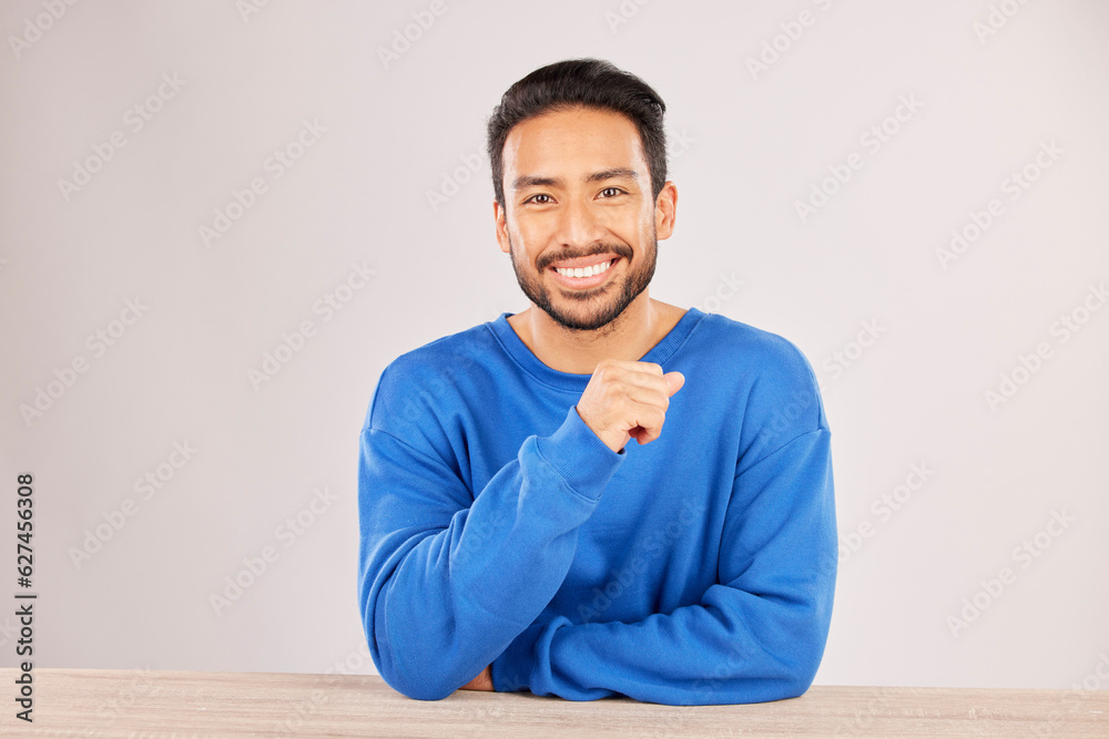 Poster smile, table and portrait of a man happy to relax on a desk feeling confident isolated in a studio w