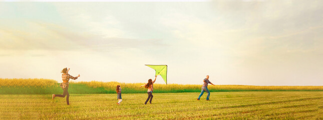 Family launches a kite in the field in summer park at sunset