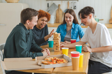 Home party. Friends spending time together playing in board game crash wooden tower at home. Happy...