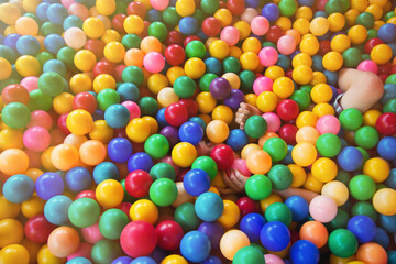 Fototapeta na wymiar Portrait of little boy lying on multi colored plastic balls in paddling pool in playing centre