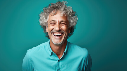 Middle-aged man laughs against a blue background. - obrazy, fototapety, plakaty