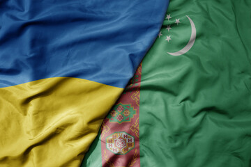 big waving national colorful flag of ukraine and national flag of turkmenistan .