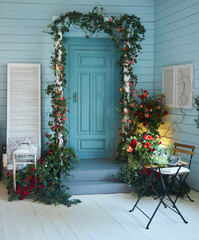 Fototapeta na wymiar Entrance door decorated with flowers and a table. The veranda of the house in a rustic style