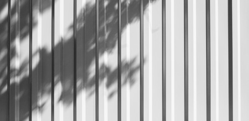 Metallic ribbed fence in gray color with shadow from tree branches.Abstract background of iron fence.