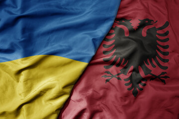 big waving national colorful flag of ukraine and national flag of albania .