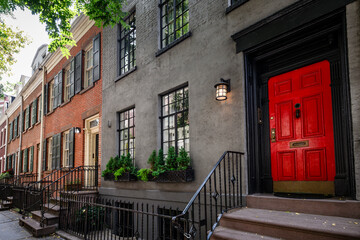 Fototapeta na wymiar View of a bright red door on a historic brownstone in Manhattan, New York City