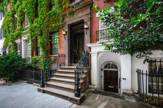 a row of brownstone buildings and stoops in an iconic neighborhood of Manhattan, New York City.