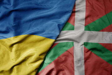 big waving national colorful flag of ukraine and national flag of basque country .