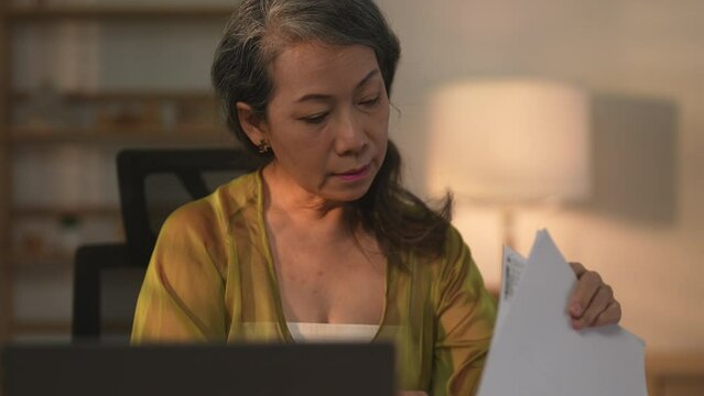 Asian female senior entrepreneur using her laptop at home.