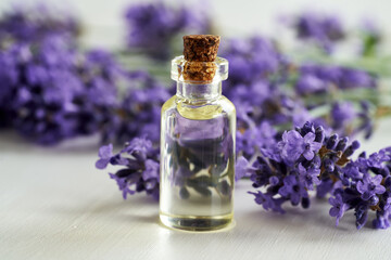 A transparent bottle of essential oil with fresh lavender flowers