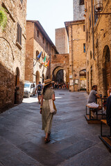 Naklejka premium Beautiful female model on the old city streets of San Gimignano, Tuscany, Italy