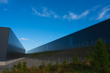 Exterior of two new and large grey warehouses.