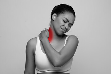 Monochrome photo of young black woman massaging sore neck