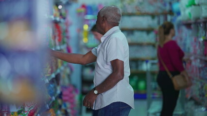 Customers shopping at grocery store aisle, Candid African American person searching for products