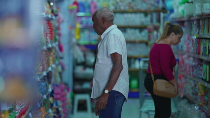 Customers shopping at grocery store aisle, Candid African American person searching for products
