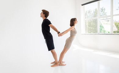 Fototapeta premium Happy calm young caucasian lady and guy in sportswear enjoy workout together, stretching body, meditate